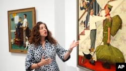 Heritage Auction's Aviva Lehmann shows paintings in Dallas, Texas, on Oct. 17, 2024, that are among works from the Boy Scouts of America's art collection that are going up for auction to help compensate tens of thousands of people who were sexually abused while in scouting.