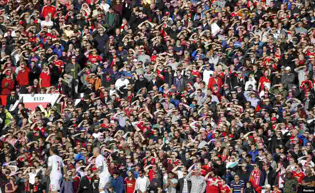 Penggemar Manchester United melindungi mata mereka dari sinar matahari dalam pertandingan sepak bola Liga Utama Barclays antara Manchester United dan Liverpool di stadion Old Trafford di Manchester, Inggris.