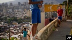 Jóvenes vuelan sus papalotes en el barrio San Agustín de Caracas, Venezuela, el lunes 3 de abril de 2023. (Foto AP/Matias Delacroix)