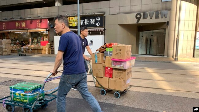 工人们在香港一家公司门前走过,其地址为中资的“中国创新投资”。(2019年11月23日)