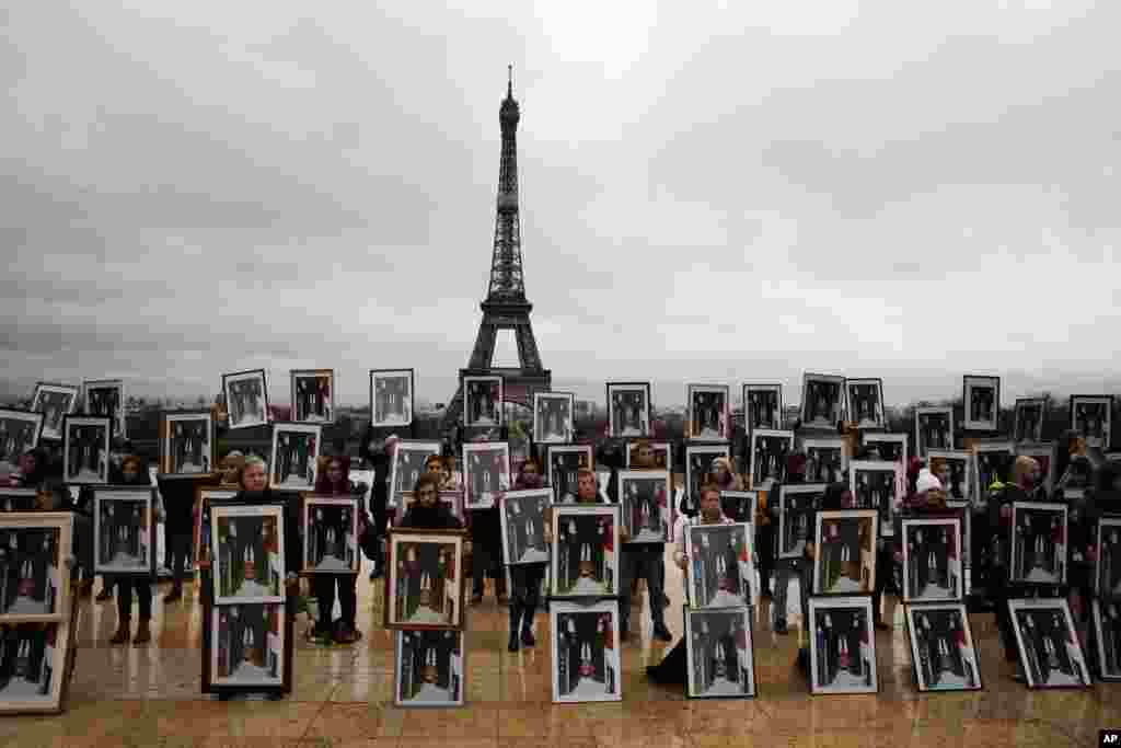 A hundred activists hold portraits of President Emmanuel Macron upside down to urge France to take action during the U.N. COP 25 climate talks in Madrid, Spain, during a gathering at Place du Trocadero facing the Eiffel Tower in Paris.