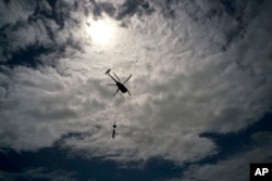 FILE - A helicopter from Whitefish Energy Holdings flies to power line towers for repairs after the passing of Hurricane Maria in Barceloneta, Puerto Rico, Oct. 15, 2017.