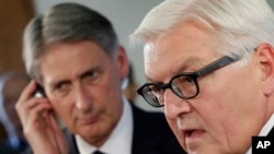 Los ministros de Relaciones Exteriores de Alemania, Frank-Walter Steinmeier, derecha, y Gran Bretaña, Philip Hammond colaborarán con envío de armas y suministros mas no atacarán.