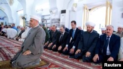 Syria's President Bashar al-Assad (3rd R) attends prayers on the first day of the Muslim holiday of Eid al-Fitr, inside a mosque in Hama, in this handout picture provided by SANA, June 25, 2017, Syria. 