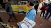 A vendor gives out copies of newspaper with a headlines of "Wuhan break out a new type of coronavirus, Hong Kong prevent SARS repeat" at a street in Hong Kong, Jan. 11, 2020.