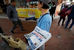 FILE - A vendor gives out copies of newspaper with a headlines of "Wuhan breakout a new type of coronavirus, Hong Kong prevents SARS repeat" at a street in Hong Kong, Jan. 11, 2020.