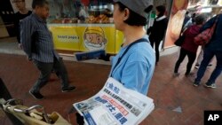 A vendor gives out copies of newspaper with a headlines of "Wuhan break out a new type of coronavirus, Hong Kong prevent SARS repeat" at a street in Hong Kong, Jan. 11, 2020.