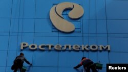 Workers wash the windows of an office building with the logo of Russia's telecom operator Rostelecom, in Moscow, Russia, May 7, 2017.