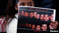 A girl holds up a poster with pictures of the 21 Egyptian Coptic Christians beheaded by Islamic State in Libya as protesters gather in a gesture to show their solidarity in front of the Egyptian Embassy in Amman, February 17, 2015.