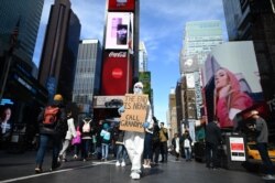A man wearing a hazmat suit and a mask holds a sign reading ‘the end is near -call grandma’ at Times Square on March 14, 2020 in New York City.