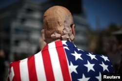 FILE - A man is seen with his head covered in bandaids protesting President Trump's proposed replacement for Obamacare, in Los Angeles, California, March 14, 2017. Despite promises during his campaign, President Donald Trump has been unable to repeal his predecessor's health care plan. Trump lays much of the blame on senior Senate Republicans.