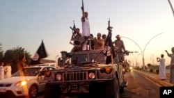 Fighters from the Islamic State group parade in a commandeered Iraqi security forces armored vehicle down a main road at the northern city of Mosul, Iraq. An independent monitoring group says some bombings carried out by the U.S.-led coalition targeting the Islamic State group likely have killed hundreds of civilians. 