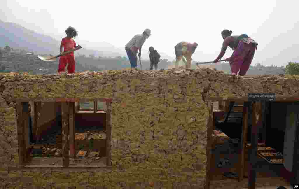 Sebuah keluarga bekerja membangun kembali rumah mereka yang hancur di Lalitpur, Nepal. Gempa 25 April menewaskan ribuan dan menghancurkan bangunan-bangunan, termasuk berbagai situs arkeologi di Kathmandu.