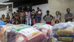 Residents wait for donated food from a campaign organized by state-run oil company Petrobras workers and the oil workers union, amid the new coronavirus pandemic, in the Vila Vintem favela in Rio de Janeiro, Brazil, Friday, Oct. 16, 2020. (AP Photo/Bruna