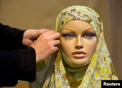 FILE - An Iranian designer sets-up a head scarf for a mannequin during an Islamic fashion exhibition at a cultural centre in Tehran. Jan. 15, 2008.