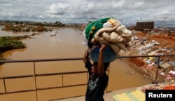 FILE - A girl carries laundry to be washed as she walks along a bridge near the banks of Ikopa river in Madagascar's capital Antananarivo.