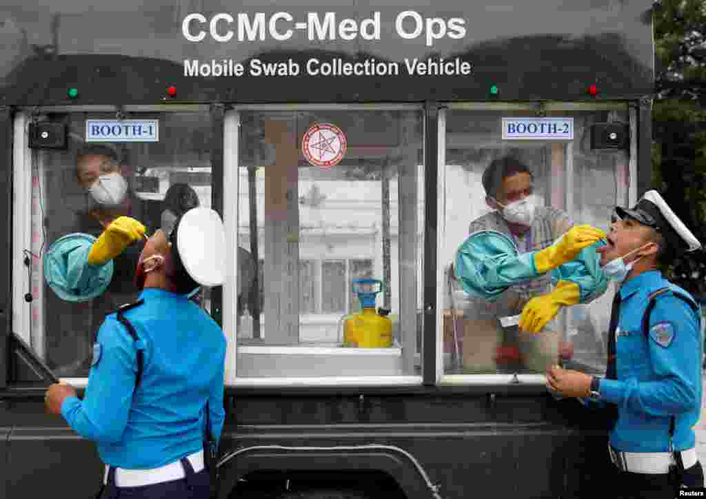 Health officials take a swab sample for the coronavirus disease (COVID-19) from traffic policemen at Singha Durbar office complex, that houses the Prime Minister&#39;s office and other ministries, in Kathmandu, Nepal.