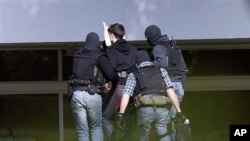 An alleged al-Qaida member, second left, is being brought to a building of the federal court in Karlsruhe, Germany, April 30, 2011