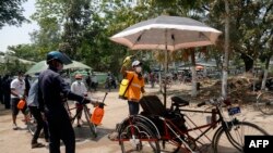 ရန်ကုန်မြို့ရှိ ဆိုက်ကားတစီးကို ပိုးသတ်ဆေးဖျန်းနေတဲ့ စေတနာ့ဝန်ထမ်းတချို့။ (ဧပြီ ၀၇၊ ၂၀၂၀)