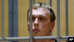 Ivan Golunov, a journalist who worked for the independent website Meduza, sits in a cage in a court room in Moscow, June 8, 2019. 