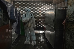 A worker wearing personal protective equipment (PPE) sprays disinfectant in the Orussey market after it was temporarily closed following a few vendors testing positive for the Covid-19 coronavirus, Phnom Penh, Cambodia, April 4, 2021. (Photo by TANG CHHIN Sothy / AFP)