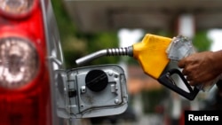 FILE - A worker fills a tank with subsidized fuel at a fuel station in Jakarta.