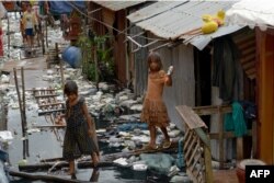 FILE - Cambodian children wade in polluted water at a village in Phnom Penh, Oct. 18, 2017.