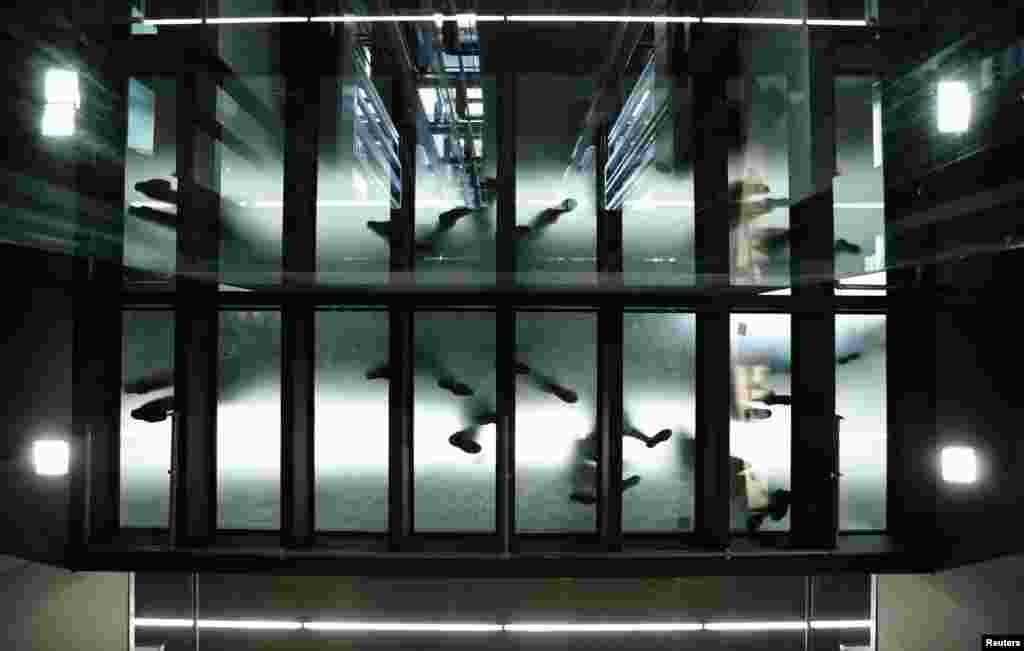 People walk on a glass passway during the opening ceremony of the new main railway station (Hauptbahnhof) in Vienna, Austria. After a construction period of five years and total construction costs of one billion Euros, the Hauptbahnhof will replace Westbahnhof and Suedbahnhof and serve as main public transport platform in the city.