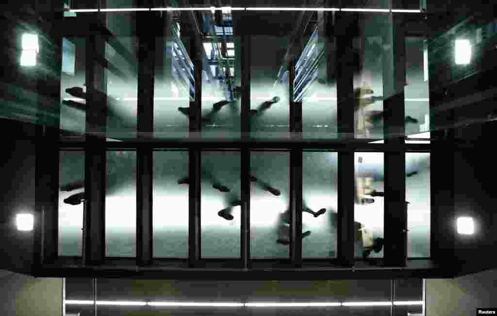 People walk on a glass passway during the opening ceremony of the new main railway station (Hauptbahnhof) in Vienna, Austria. After a construction period of five years and total construction costs of one billion Euros, the Hauptbahnhof will replace Westbahnhof and Suedbahnhof and serve as main public transport platform in the city.