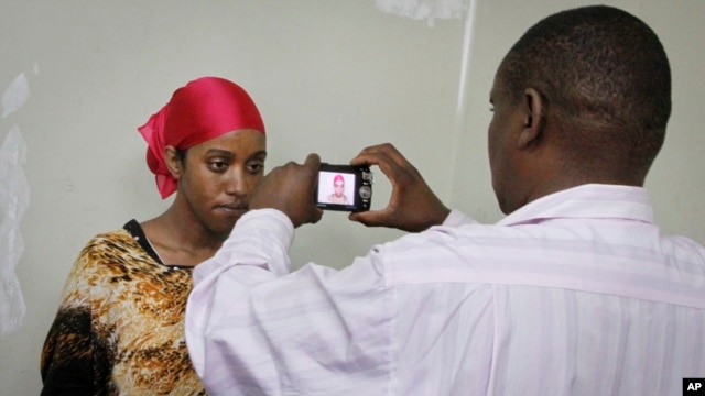 A detained Somali woman has her photograph taken before being fingerprinted and screened at the Kasarani sports stadium, which has been converted into a detention facility to hold those arrested during recent security crackdowns, near Nairobi in Kenya, April 9, 2014.