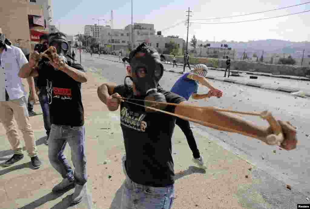 Palestinian protesters use slingshots to hurl stones at Israeli troops following a demonstration against the Israeli offensive in Gaza, in the West Bank town of Bethlehem.
