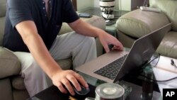 FILE - In this Sept. 18, 2012, file photo, veteran rights activist Huang Qi works on his laptop in his home in Chengdu in southwestern China's Sichuan province. 