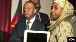 Cameroon's higher education minister, Jacques Fame Ndongo, hands a laptop to a female student, at the University of Yaounde II, in Soa, south of Yaounde, Cameroon, Dec. 27, 2017. (M. Kindzeka/VOA)