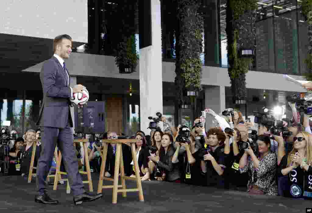 Former England soccer star David Beckham holds a soccer ball at a Miami news conference where he announced he will exercise his option to purchase a Major League Soccer expansion team in Miami, Florida. 