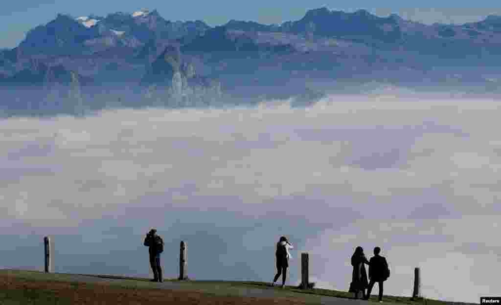 People enjoy the view of fog-covered valleys during sunny autumn weather near the peak of Mount Rigi, Switzerland.
