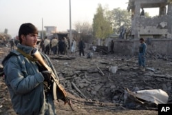 Afghan security members inspect the site of a suicide car bombing at Surkh Rud district in Nangarhar province, east of Kabul, Afghanistan, Dec. 7, 2015.