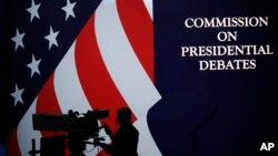 A cameraman is silhouetted against an an American flag during preparations for the presidential debate at Hofstra University in Hempstead, N.Y., Sept. 25, 2016.