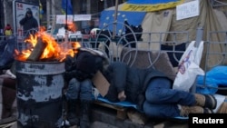 People sleep in a protesters' tent camp in the early morning hours, during a rally to support EU integration in Kyiv, Dec. 5, 2013. 