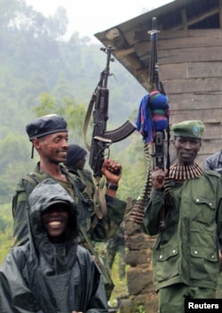 M23 rebel fighters stand in the rain at Rumangabo after government troops abandoned the town, north of the eastern Congolese city of Goma, July 28, 2012.