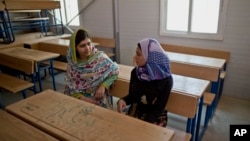 Nobel Peace Prize laureate Malala Yousafzai, 18, left, and Mezon al-Melihan, a 17-year-old refugee from the southern Syrian town of Deraa, talk while visiting a class at Azraq refugee camp, Jordan, July 13, 2015. 
