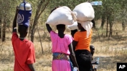 Para perempuan dan anak perempuan berjalan pulang setelah mengambil bahan makanan di Bentiu, sekitar 38 kilometer melalui jalan setapak di semak-semak untuk menghindari penyerangan di jalan utama, dekat Nhialdu, di Sudan Selatan, 7 Desember 2018.