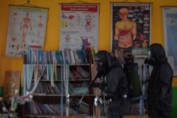 Seorang petugas medis meyemprotkan disinfektan di sebuah sekolah di Palu, Sulawesi Tengah, untuk mencegah penyebaran virus corona baru (COVID-19), 20 Maret 2020. (Foto: Antara via Reuters)