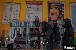 Seorang petugas medis meyemprotkan disinfektan di sebuah sekolah di Palu, Sulawesi Tengah, untuk mencegah penyebaran virus corona baru (COVID-19), 20 Maret 2020. (Foto: Antara via Reuters)