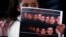 A girl holds up a poster with pictures of the 21 Egyptian Coptic Christians beheaded by Islamic State in Libya as protesters gather in a gesture to show their solidarity in front of the Egyptian Embassy in Amman, February 17, 2015.