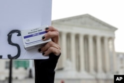 FILE - An abortion- rights activist holds a box of mifepristone pills as demonstrators from both anti-abortion and abortion-rights groups rally outside the Supreme Court in Washington, March 26, 2024.