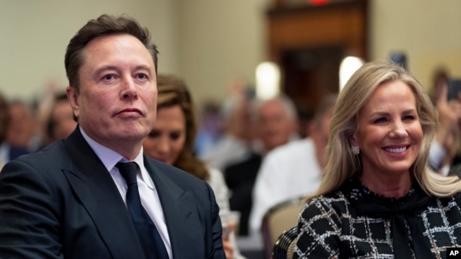 Elon Musk, left, sits with Kelly Johnson, wife of House Speaker Mike Johnson, as President-elect Donald Trump speaks at a meeting of the House Republican conference, in Washington, Nov. 13, 2024.