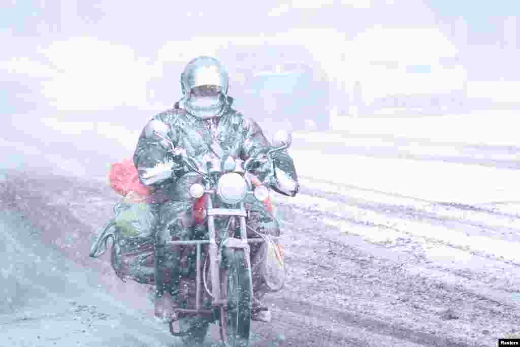 A motorcyclist rides amid snow in Dalian, Liaoning province, China, Dec.16. 2017.