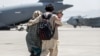 A family walks towards a US Air Force Boeing C-17 Globemaster III during an evacuation at Hamid Karzai International Airport, Afghanistan, Aug. 22, 2021. (US Marine Corps photo)