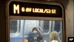 In this March 19, 2020 photo, a commuter wears a face mask while riding the subway in New York. 
