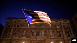 Seorang demonstran melambaikan bendera Catalan pro-kemerdekaan di luar Palau Generalitat, dalam sebuah demonstrasi menentang keputusan hakim untuk memenjarakan mantan anggota pemerintah Catalan, di Barcelona, Spanyol, Jumat, 3 November 2017.